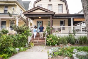 Black couple moving down front steps of two-story house