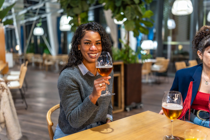 Latin woman enjoying beer talking to friends