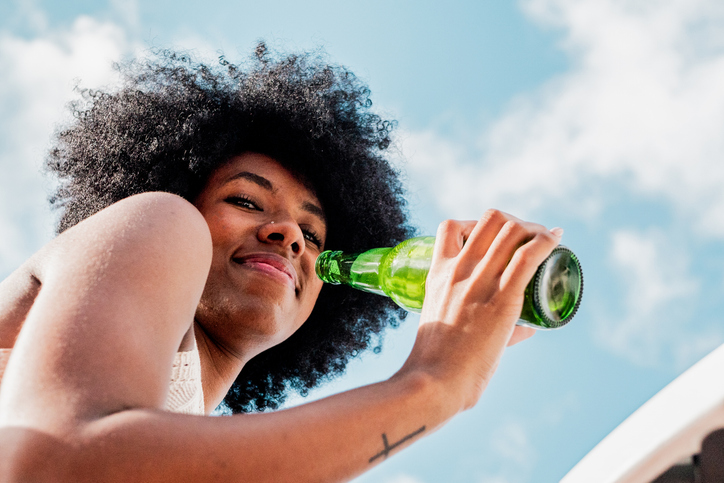 Portrait of young woman drinking beer outdoors