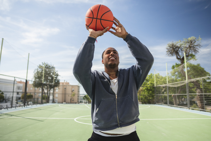 Young basketball player shooting on outdoor court