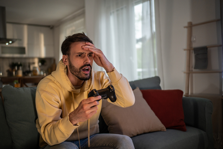 Stressed gamer losing while playing videogames on the couch at home