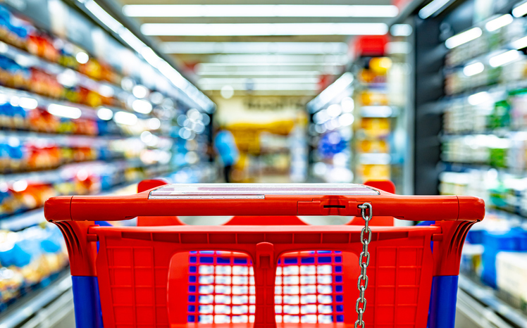 A shopping cart by a store shelf in a supermarket